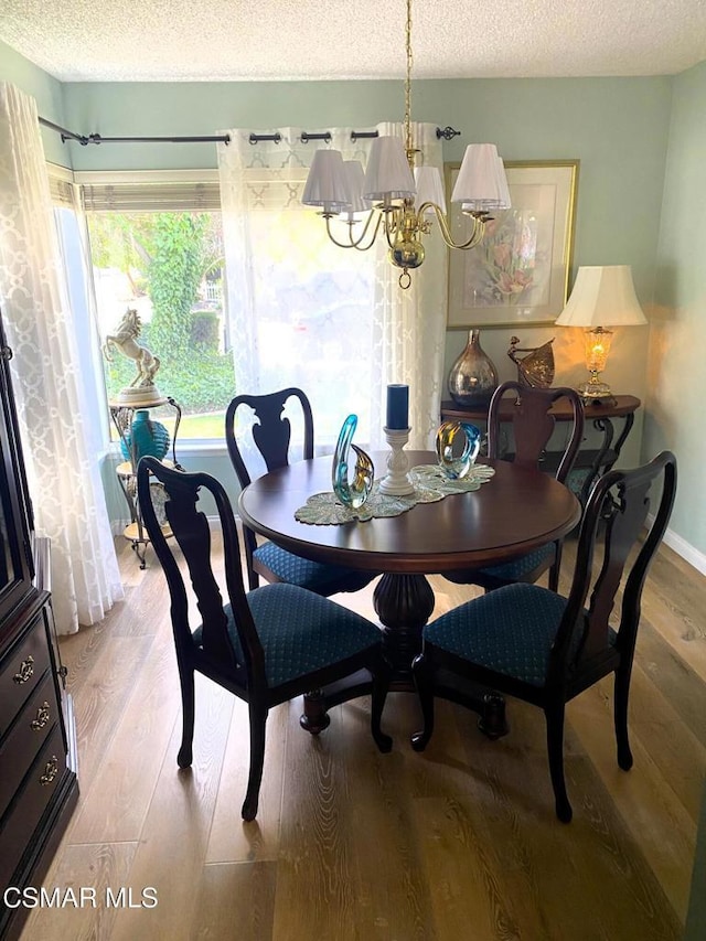 dining area featuring an inviting chandelier, light hardwood / wood-style floors, and a textured ceiling