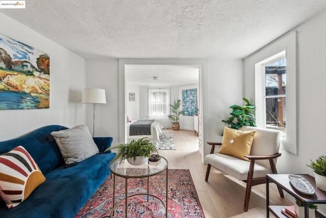 living room with a healthy amount of sunlight, light hardwood / wood-style flooring, and a textured ceiling