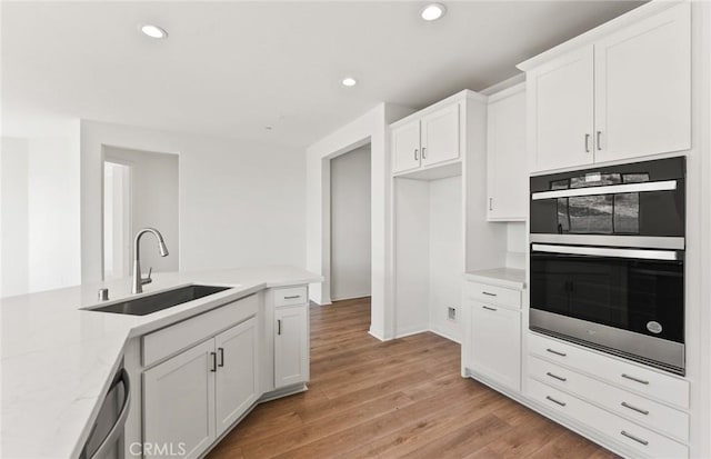 kitchen featuring sink, dishwasher, white cabinetry, double wall oven, and light hardwood / wood-style floors