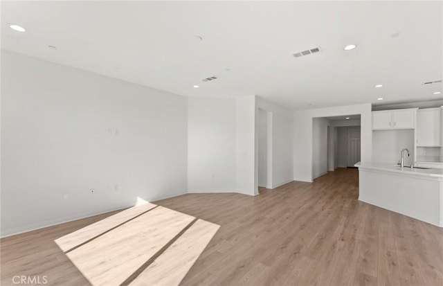 unfurnished living room featuring sink and light wood-type flooring