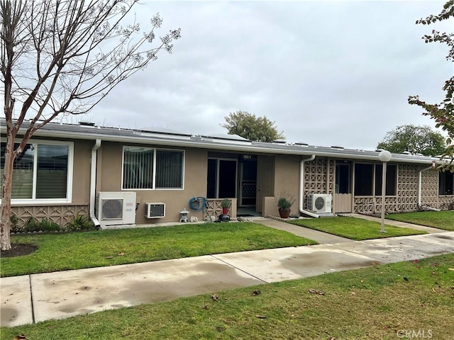 single story home with ac unit, a front yard, and a wall mounted AC