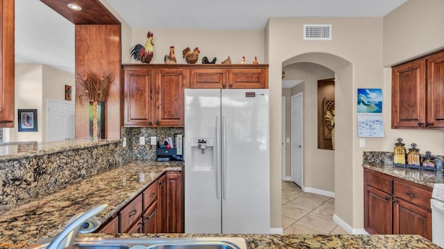 kitchen with tasteful backsplash, white appliances, light tile patterned flooring, and stone countertops