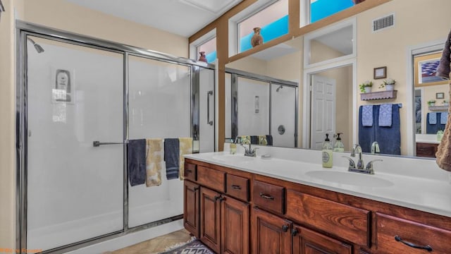 bathroom featuring vanity, a shower with shower door, and tile patterned floors