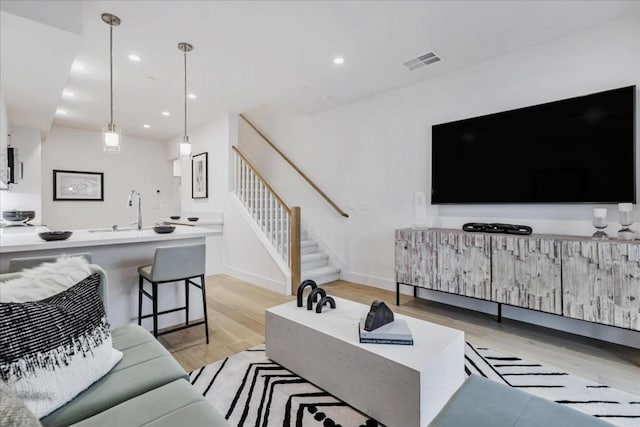 living room featuring sink and light hardwood / wood-style flooring