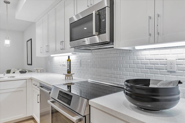 kitchen featuring stainless steel appliances, white cabinetry, and pendant lighting