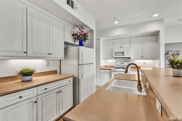 kitchen with white cabinetry, sink, and white appliances