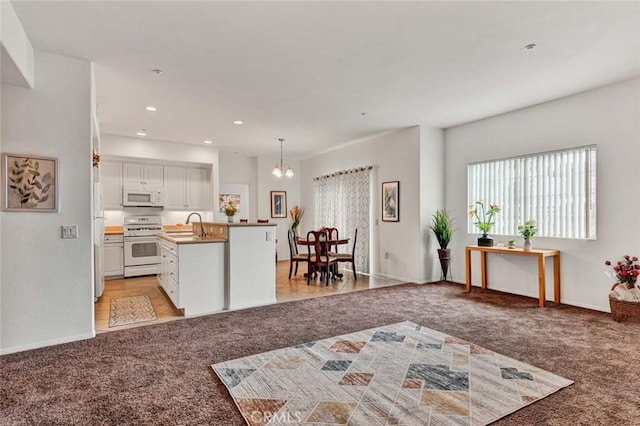 kitchen featuring sink, light carpet, pendant lighting, white appliances, and white cabinets