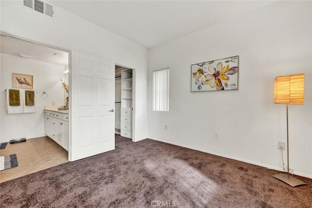 unfurnished bedroom featuring ensuite bathroom and dark carpet