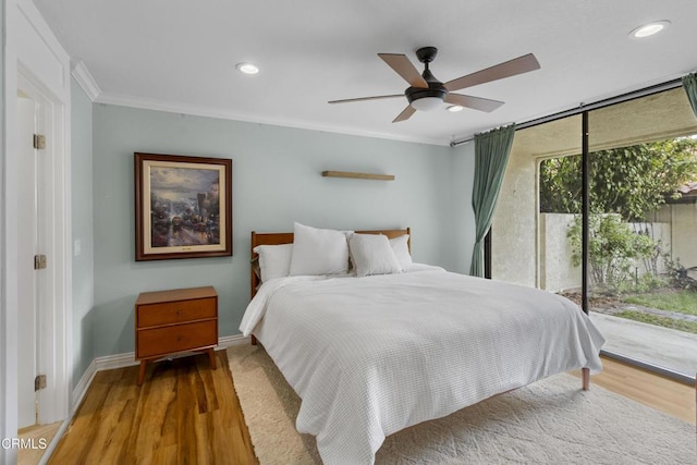 bedroom with crown molding, expansive windows, hardwood / wood-style flooring, and access to outside