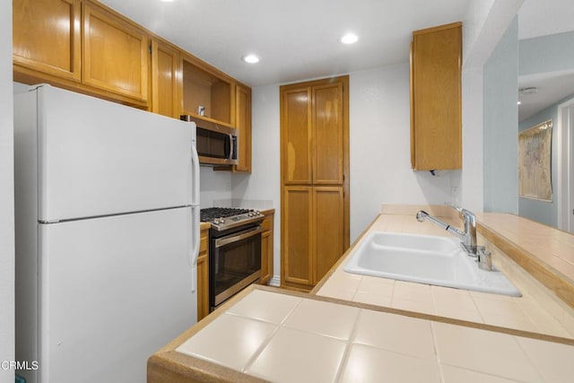 kitchen featuring sink, tile counters, kitchen peninsula, and appliances with stainless steel finishes