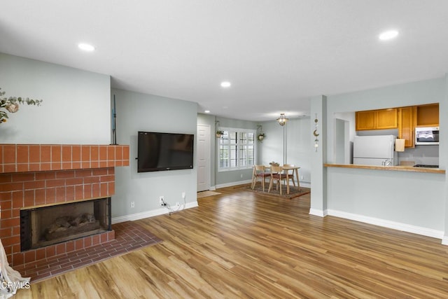 unfurnished living room with a tiled fireplace and light hardwood / wood-style flooring