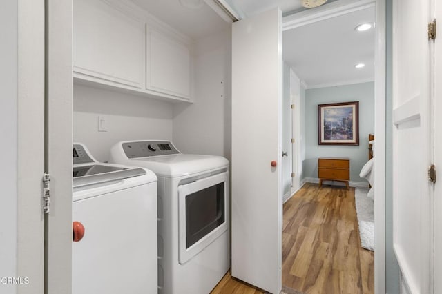 laundry room with light hardwood / wood-style flooring, ornamental molding, cabinets, and washing machine and clothes dryer