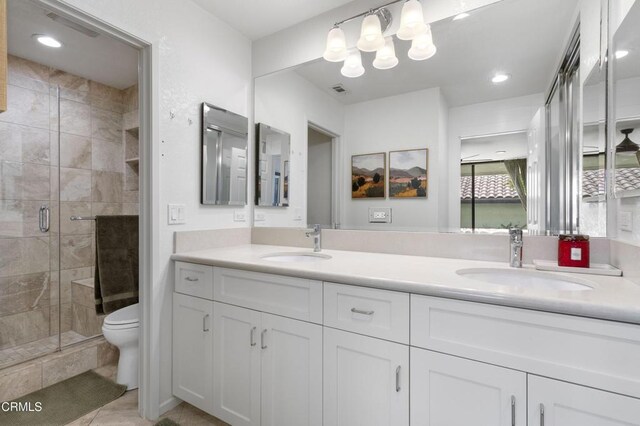 bathroom featuring vanity, toilet, tile patterned flooring, and a shower with door