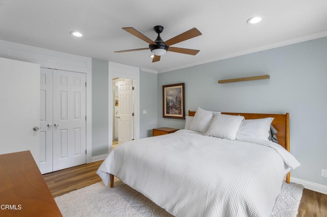 bedroom with wood-type flooring, ceiling fan, crown molding, ensuite bath, and a closet