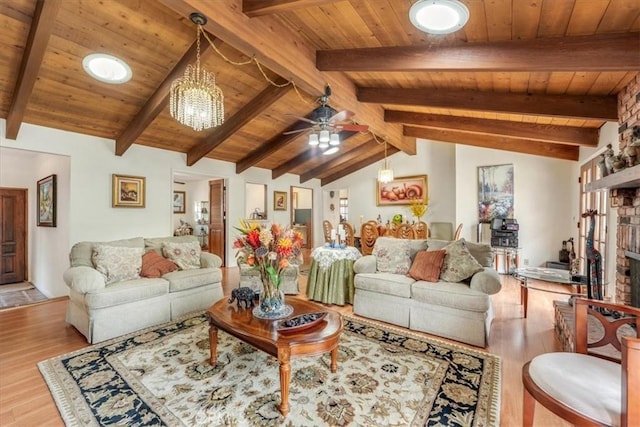 living room with a brick fireplace, vaulted ceiling with beams, ceiling fan with notable chandelier, and light hardwood / wood-style floors