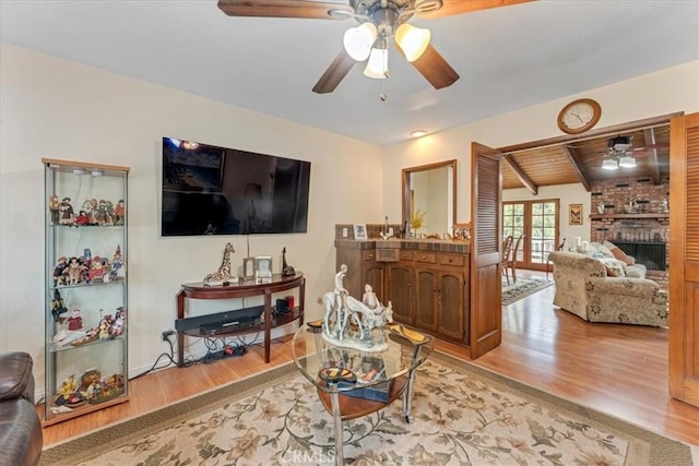 living room featuring a fireplace, lofted ceiling with beams, ceiling fan, wood ceiling, and light hardwood / wood-style flooring