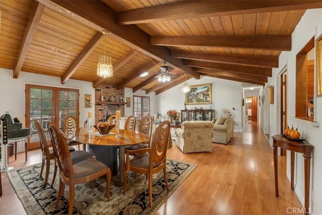 dining room with a fireplace, french doors, vaulted ceiling with beams, wooden ceiling, and light hardwood / wood-style flooring