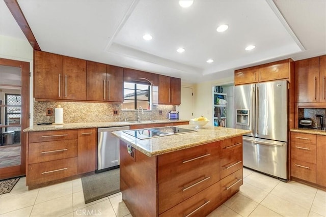 kitchen with a center island, backsplash, a raised ceiling, and appliances with stainless steel finishes