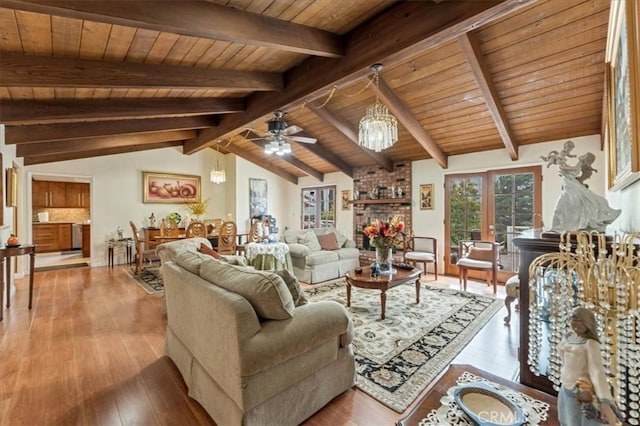 living room with lofted ceiling with beams, ceiling fan with notable chandelier, light hardwood / wood-style floors, and wooden ceiling