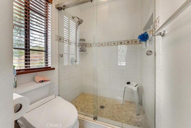 bathroom with toilet and a shower with door