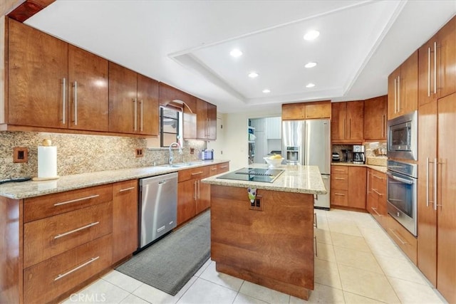 kitchen featuring sink, appliances with stainless steel finishes, a kitchen island, decorative backsplash, and a raised ceiling