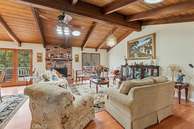 living room with light hardwood / wood-style floors, lofted ceiling with beams, a brick fireplace, wooden ceiling, and french doors