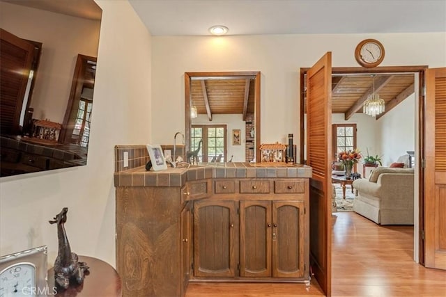 bar featuring lofted ceiling with beams, tile countertops, wood ceiling, and light hardwood / wood-style flooring