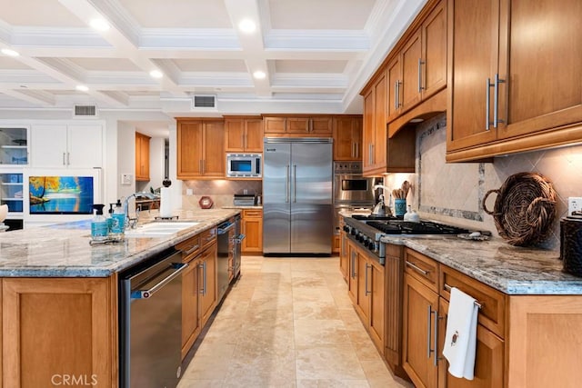 kitchen featuring sink, built in appliances, light stone counters, beam ceiling, and a spacious island