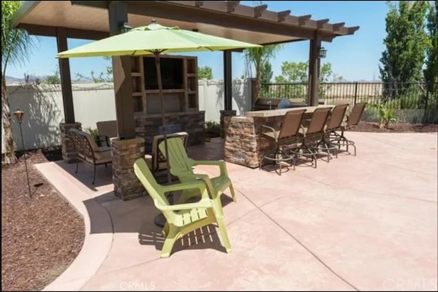 view of patio / terrace with exterior fireplace, a fenced backyard, and outdoor dry bar