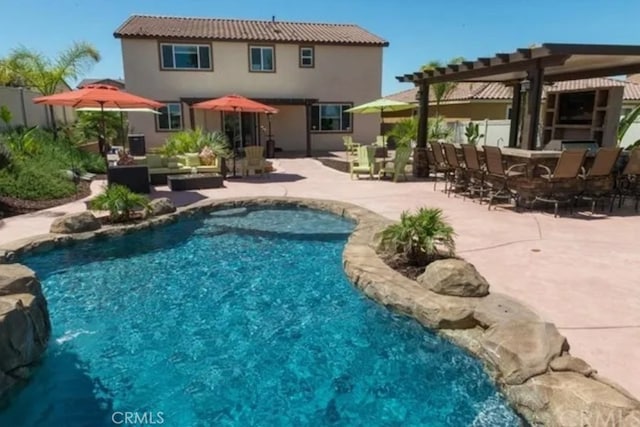 back of property featuring an outdoor pool, outdoor dry bar, a patio area, an outdoor living space, and a pergola