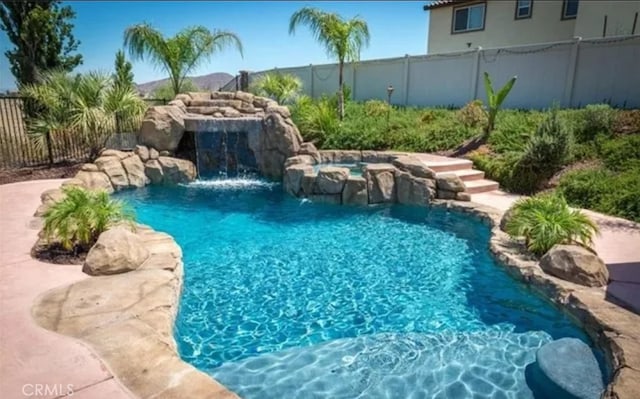 view of swimming pool featuring fence, a fenced in pool, and an in ground hot tub