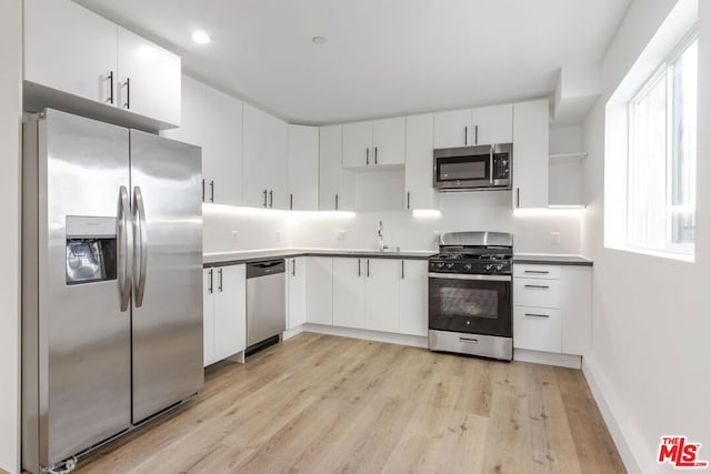 kitchen featuring white cabinetry, sink, light wood-type flooring, and appliances with stainless steel finishes