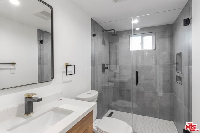 bathroom featuring vanity, a shower with shower door, and toilet