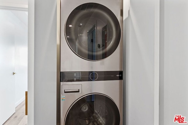 laundry area featuring stacked washing maching and dryer and light hardwood / wood-style floors