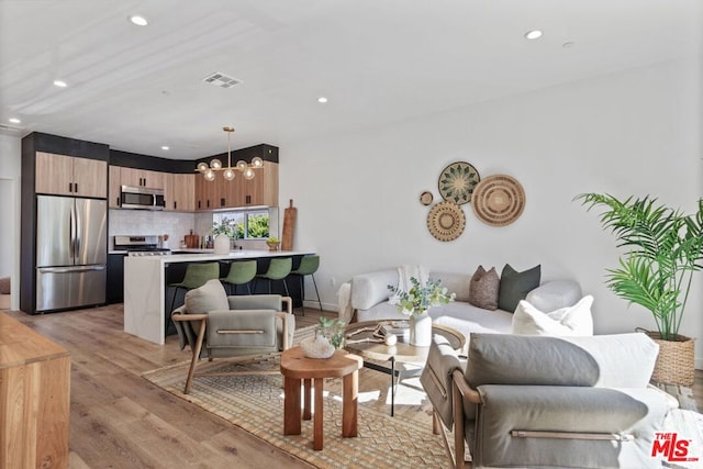 living room with an inviting chandelier and light wood-type flooring