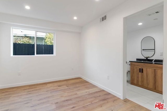 spare room featuring sink and light hardwood / wood-style flooring