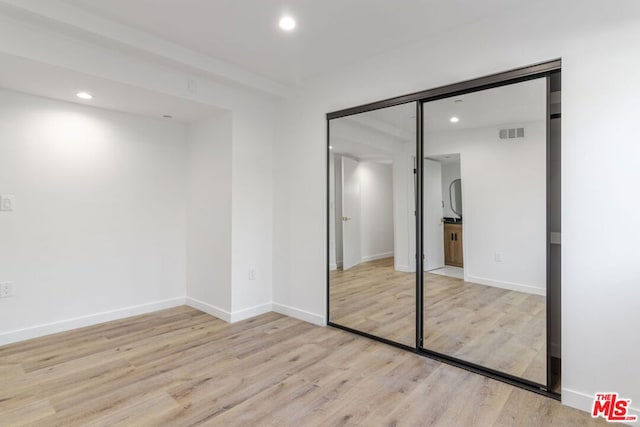 unfurnished bedroom featuring light hardwood / wood-style floors and a closet