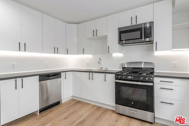 kitchen featuring stainless steel appliances, white cabinetry, sink, and light hardwood / wood-style flooring