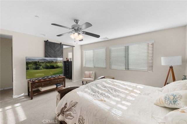 bedroom featuring ceiling fan, a barn door, and light carpet