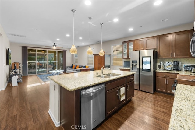 kitchen with appliances with stainless steel finishes, decorative light fixtures, sink, dark hardwood / wood-style flooring, and light stone counters