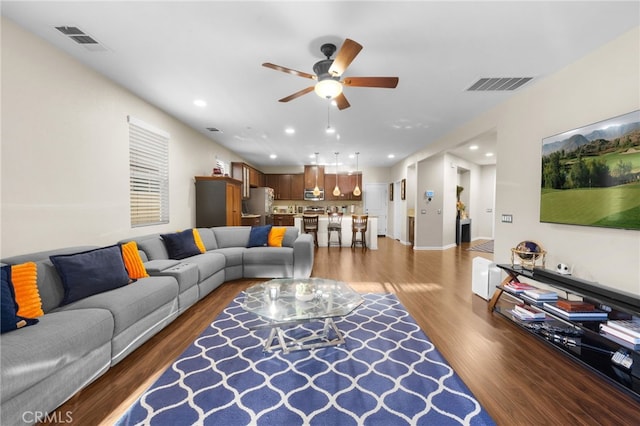 living room featuring ceiling fan and dark hardwood / wood-style flooring