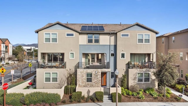 view of front of house featuring a balcony and solar panels