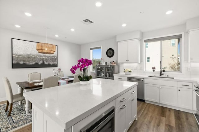 kitchen featuring white cabinetry, stainless steel appliances, a center island, and sink