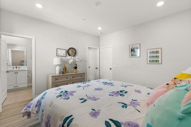 bedroom featuring connected bathroom and light wood-type flooring