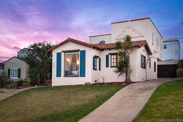 mediterranean / spanish-style home featuring a garage and a lawn