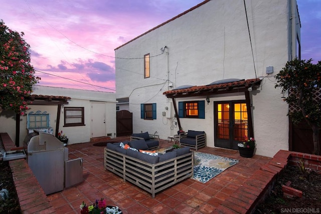 back house at dusk featuring area for grilling, an outdoor living space, and a patio