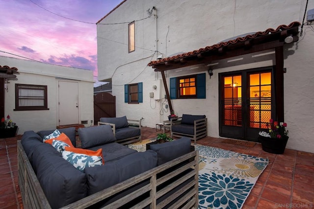 patio terrace at dusk with an outdoor living space and french doors