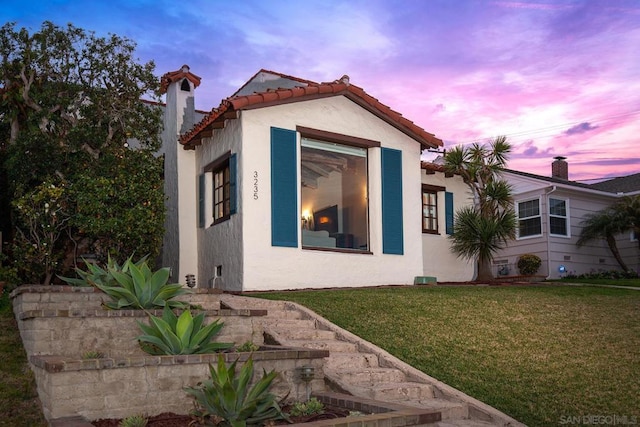 property exterior at dusk with a lawn