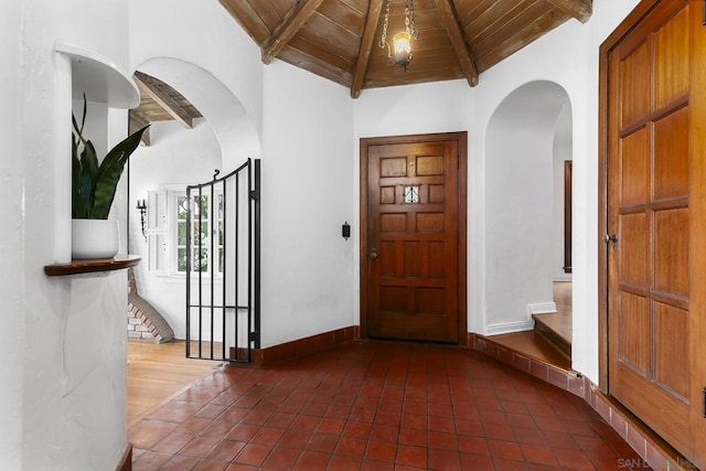 foyer entrance featuring wood ceiling, beam ceiling, and dark tile patterned flooring