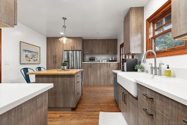 kitchen featuring pendant lighting, sink, a center island, stainless steel appliances, and light wood-type flooring